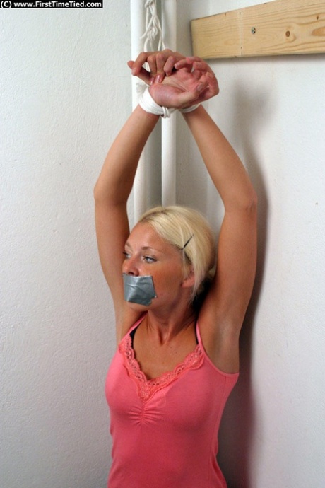 Clothed blonde is shut up with duct over mouth and wrists tied together