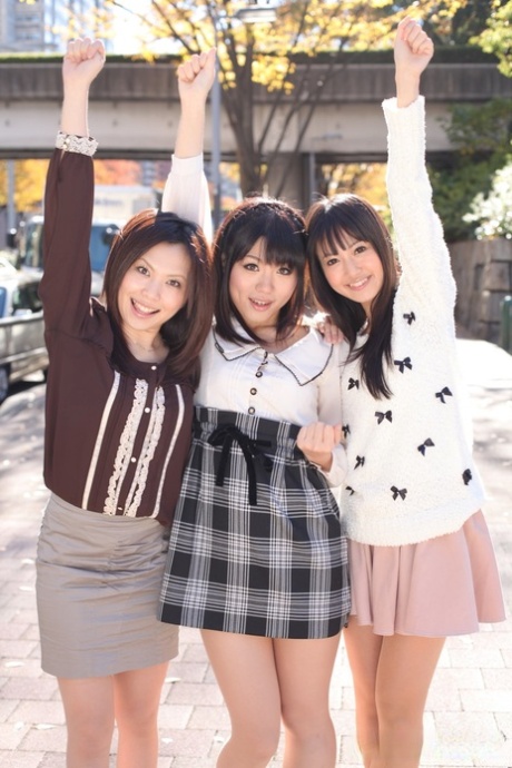 Three Japanese girls in skirts pose outdoors for a SFW shoot