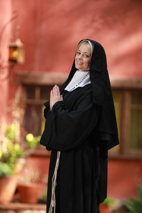 Blonde nun Charlotte Stokely exposes her small boobs and nice ass in the yard