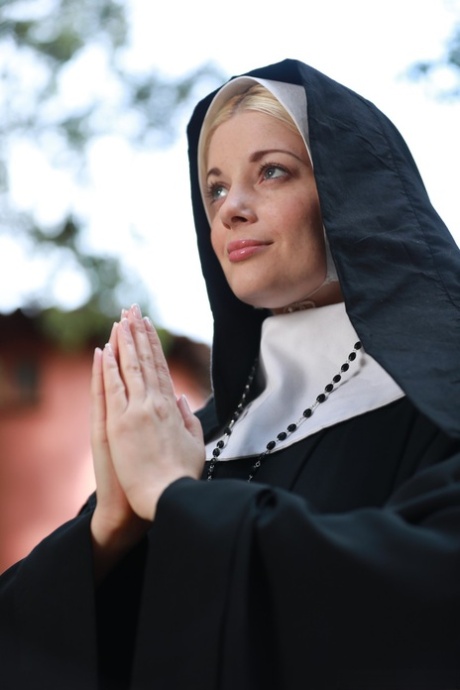 Blonde nun Charlotte Stokely exposes her small boobs and nice ass in the yard