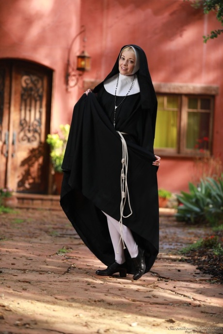 Blonde nun Charlotte Stokely exposes her small boobs and nice ass in the yard