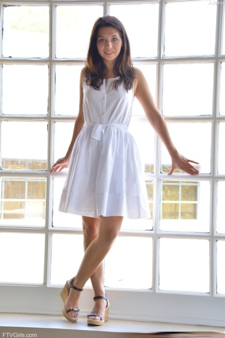 Brunette babe Ariana shows her cunt before doffing her white dress and posing